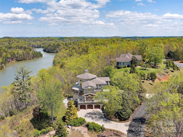 birds eye view of property with a wooded view and a water view