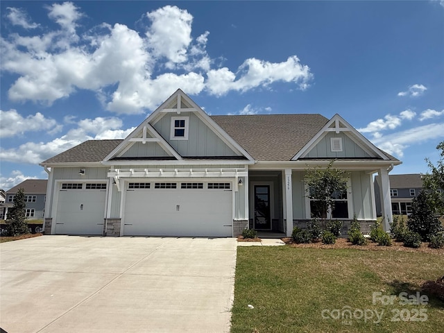 craftsman-style home featuring a shingled roof, a garage, board and batten siding, a front yard, and concrete driveway