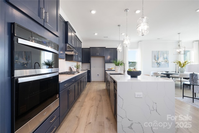 13279 Arnold Palmer Cir Unit 867, Lancaster, SC 29720 - kitchen with stainless steel appliances, light stone countertops, a center island with sink, decorative light fixtures, and light wood finished floors