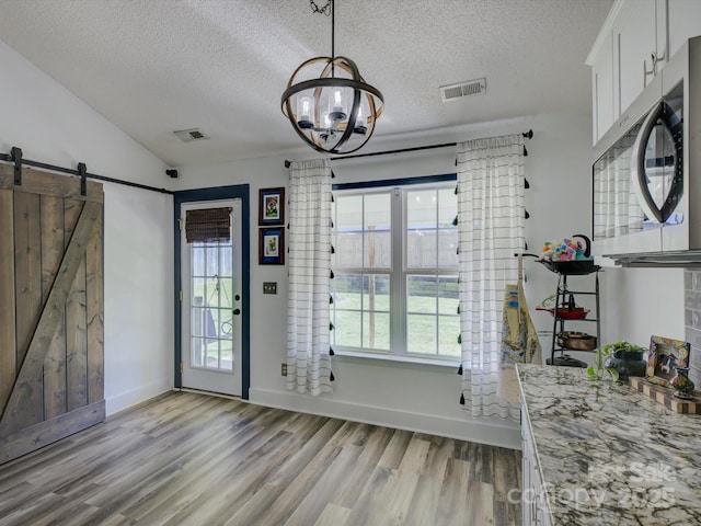 1488 Meadow Glen Ln, Rock Hill, SC 29730 - dining area featuring a textured ceiling, light wood-type flooring, a barn door, a chandelier, and baseboards