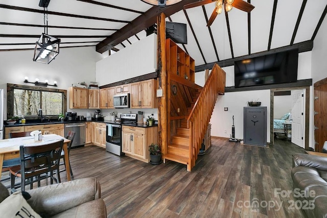 kitchen with stainless steel appliances, open floor plan, dark countertops, ceiling fan, and high vaulted ceiling