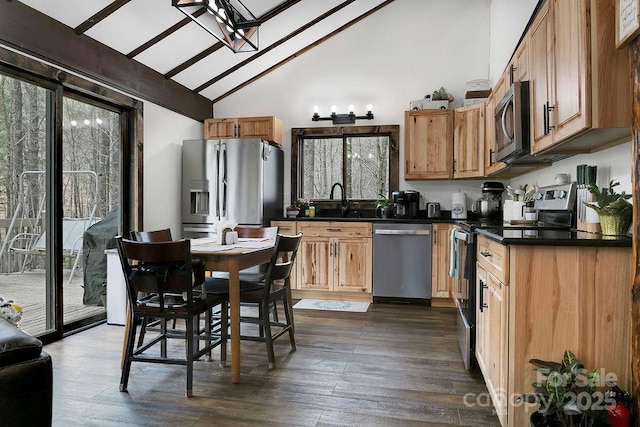 kitchen with high vaulted ceiling, dark countertops, beamed ceiling, appliances with stainless steel finishes, and dark wood-style floors