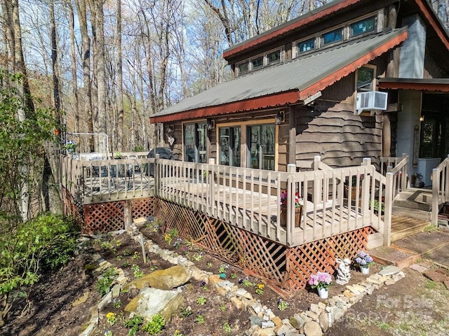 exterior space with a wooden deck, cooling unit, and metal roof