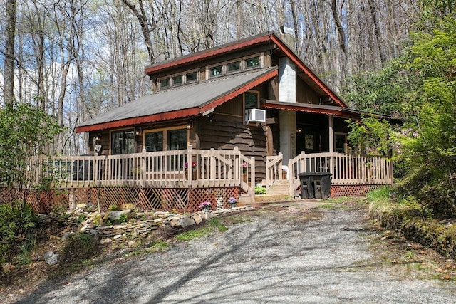 rustic home featuring cooling unit, a porch, and metal roof