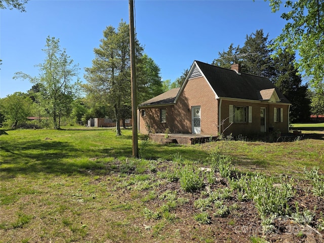 view of home's exterior with brick siding, a chimney, and a lawn