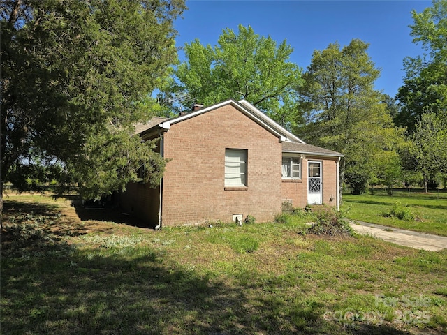 view of home's exterior with brick siding and a lawn