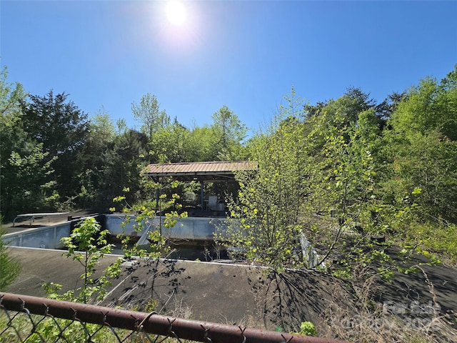 exterior space featuring a vegetable garden, a view of trees, metal roof, and a gazebo