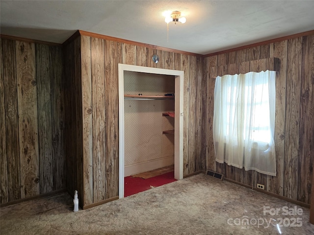 unfurnished bedroom featuring wood walls, baseboards, carpet flooring, and visible vents