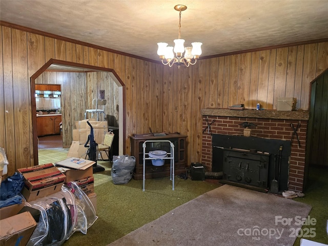 carpeted living area featuring wood walls, arched walkways, a brick fireplace, and a chandelier
