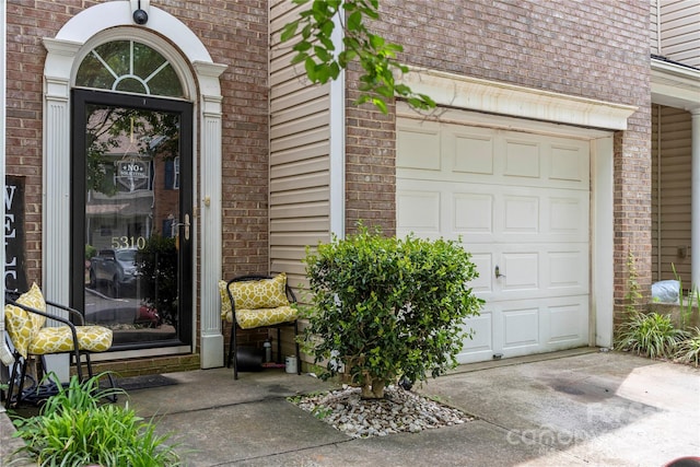 property entrance with an attached garage and brick siding