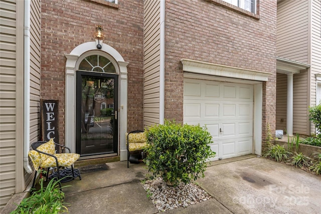entrance to property with driveway, brick siding, and a garage
