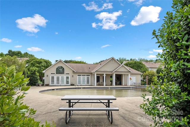 back of property with roof with shingles, a patio area, french doors, and a community pool
