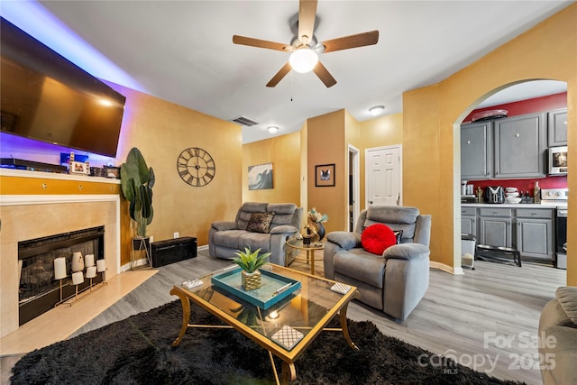 living area with visible vents, a ceiling fan, light wood-style flooring, and arched walkways