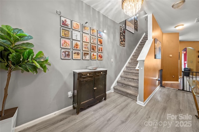 stairway featuring arched walkways, wood finished floors, and baseboards