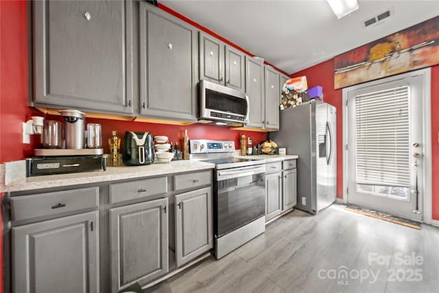 kitchen with light wood-style flooring, visible vents, appliances with stainless steel finishes, and gray cabinets
