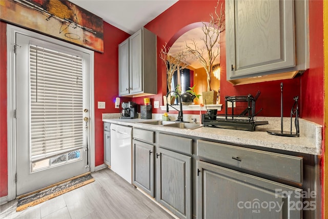 kitchen featuring baseboards, white dishwasher, light countertops, and a sink