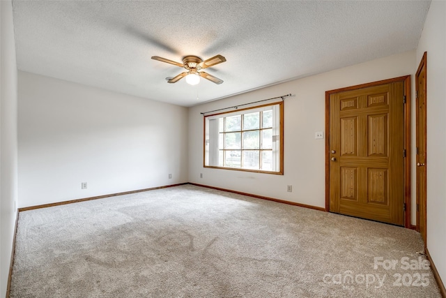 empty room with carpet floors, a textured ceiling, ceiling fan, and baseboards