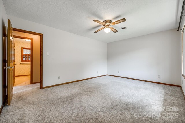 spare room with visible vents, a ceiling fan, carpet, and baseboards