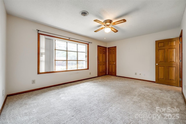 unfurnished room featuring light colored carpet, a ceiling fan, baseboards, and visible vents
