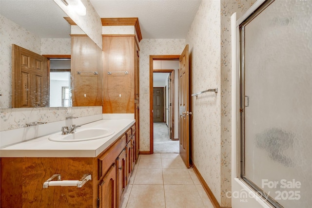 full bath with tile patterned flooring, vanity, a textured ceiling, wallpapered walls, and baseboards