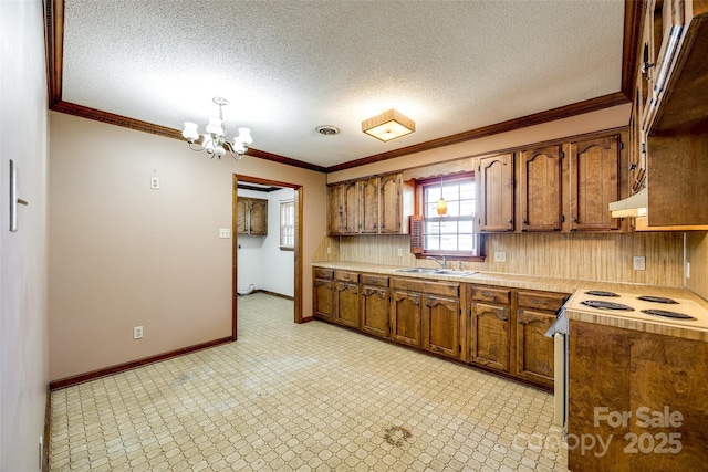 kitchen featuring white electric range, a sink, light countertops, a notable chandelier, and ornamental molding