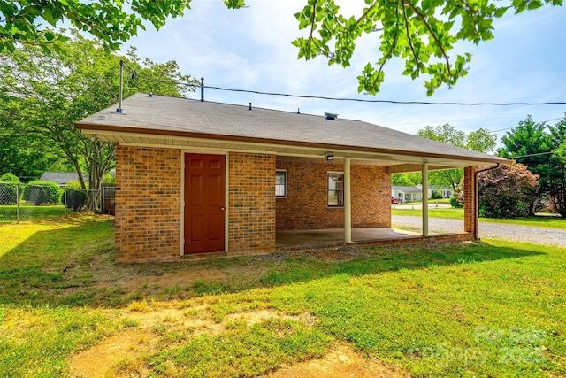exterior space with a lawn, brick siding, fence, and gravel driveway