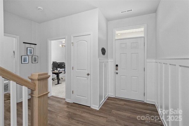 foyer featuring a wainscoted wall, dark wood-type flooring, and visible vents