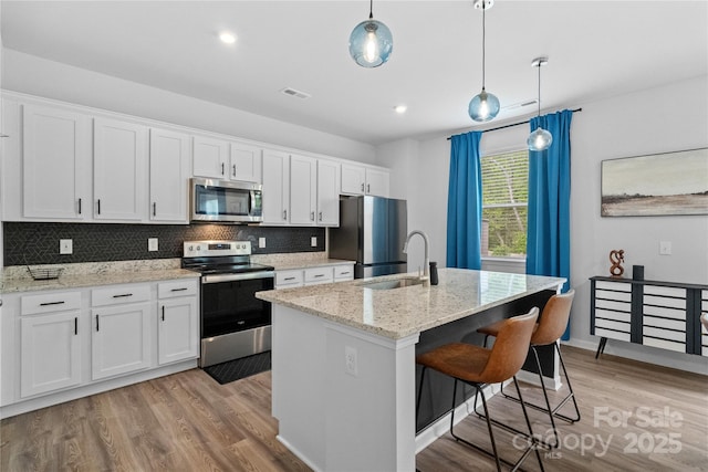 kitchen featuring a sink, decorative backsplash, light wood-type flooring, appliances with stainless steel finishes, and visible vents