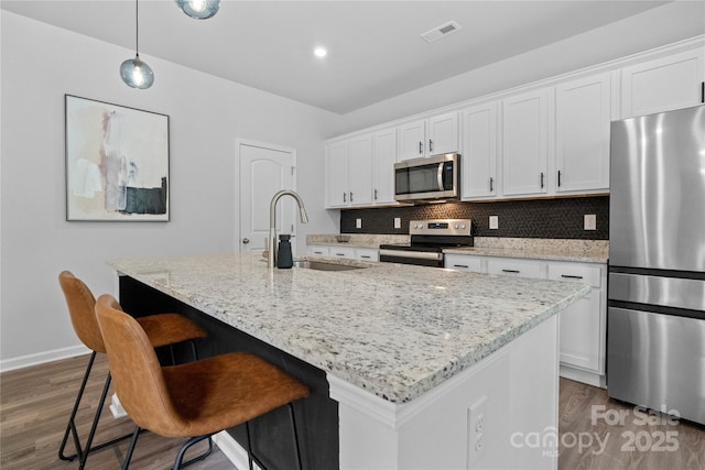 kitchen featuring white cabinets, wood finished floors, visible vents, a sink, and appliances with stainless steel finishes