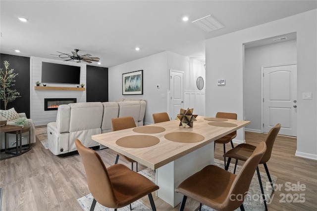 dining area with recessed lighting, a ceiling fan, baseboards, light wood-style flooring, and a large fireplace