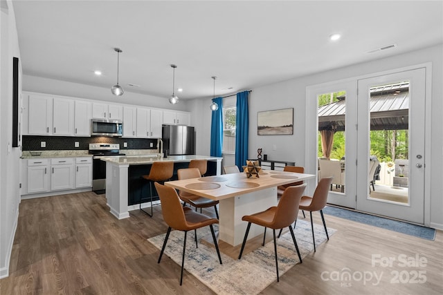 dining room with light wood-style floors, visible vents, a wealth of natural light, and recessed lighting