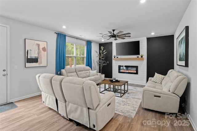 living area with a ceiling fan, wood finished floors, a fireplace, and recessed lighting