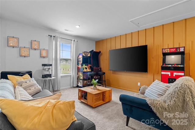 living area with attic access, baseboards, visible vents, and light colored carpet