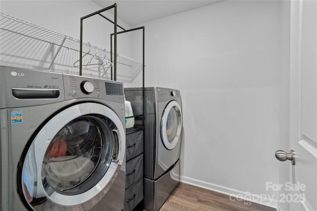 laundry area featuring washer and dryer, baseboards, wood finished floors, and laundry area