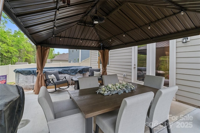 view of patio featuring fence, outdoor dining area, and a gazebo