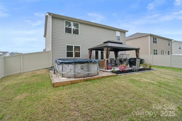 rear view of property featuring a fenced in pool, a fenced backyard, a gazebo, a lawn, and a patio