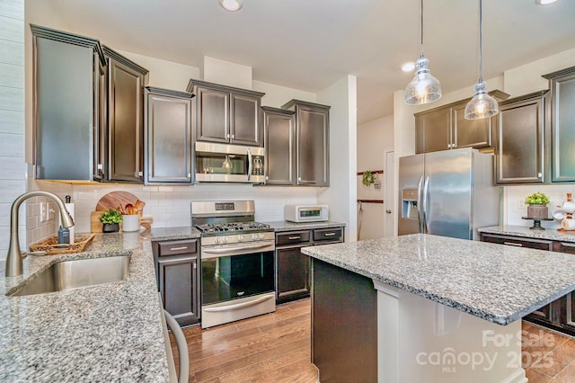17231 Rider Wood Ln, Charlotte, NC 28278 - kitchen featuring appliances with stainless steel finishes, a sink, light wood-style floors, light stone counters, and decorative backsplash