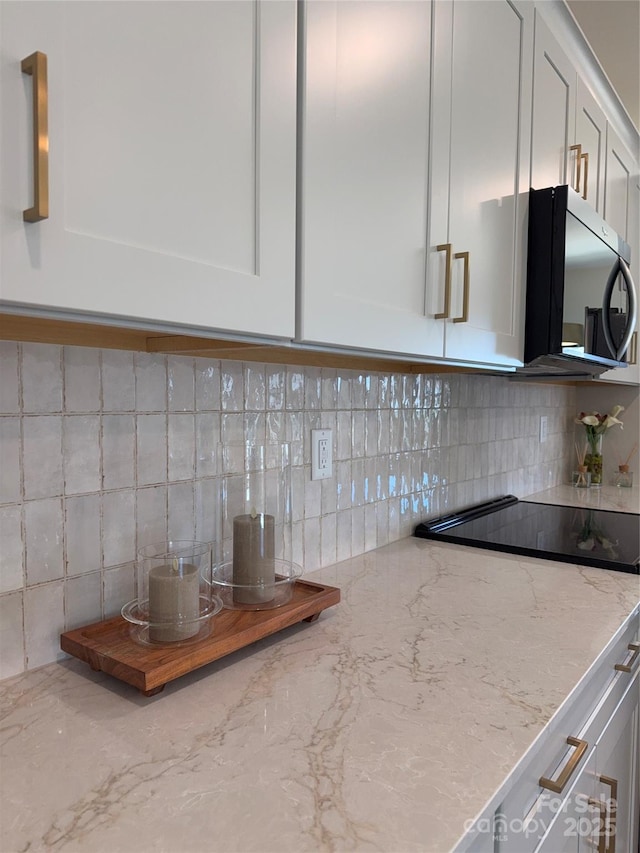 kitchen featuring decorative backsplash, white cabinetry, and light stone countertops