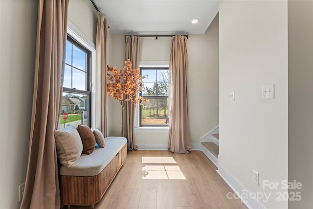sitting room with plenty of natural light, stairway, light wood-style floors, and baseboards