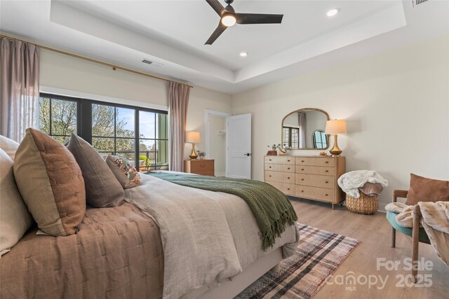 bedroom with visible vents, a raised ceiling, ceiling fan, recessed lighting, and light wood-style flooring