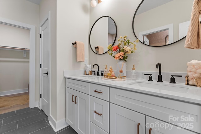 full bathroom featuring tile patterned floors, double vanity, a sink, and a walk in closet