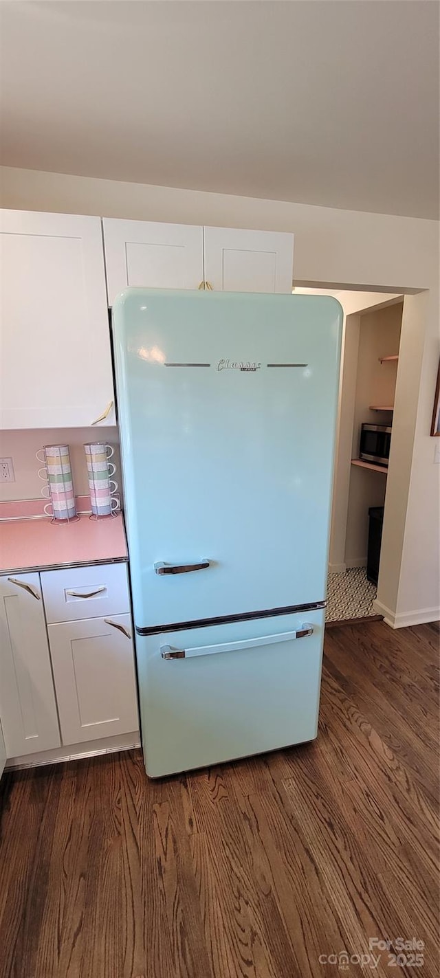 219 Flat Creek Rd, Black Mountain, NC 28711 - interior details featuring stainless steel microwave, dark wood-style flooring, white cabinetry, and freestanding refrigerator