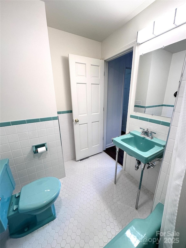 219 Flat Creek Rd, Black Mountain, NC 28711 - bathroom with tile patterned floors, toilet, wainscoting, tile walls, and a sink