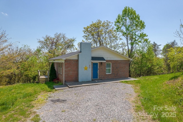 963 Kenham Pl SW, Lenoir, NC 28645 - view of front of house featuring brick siding, a front lawn, a deck, and a chimney