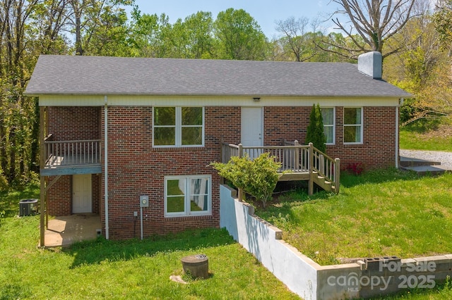 963 Kenham Pl SW, Lenoir, NC 28645 - back of house with central air condition unit, a chimney, brick siding, a deck, and a lawn