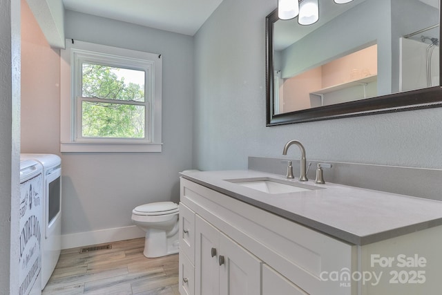 963 Kenham Pl SW, Lenoir, NC 28645 - bathroom featuring separate washer and dryer, vanity, toilet, wood finished floors, and baseboards