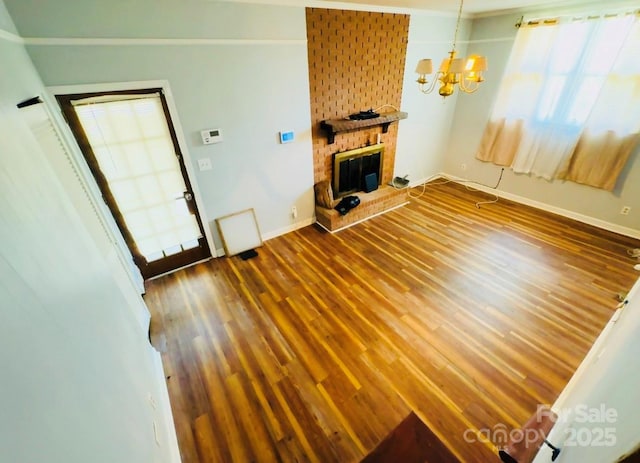 2480 Sumter Hwy, Bishopville, SC 29010 - unfurnished living room with wood finished floors, a brick fireplace, a notable chandelier, and a healthy amount of sunlight