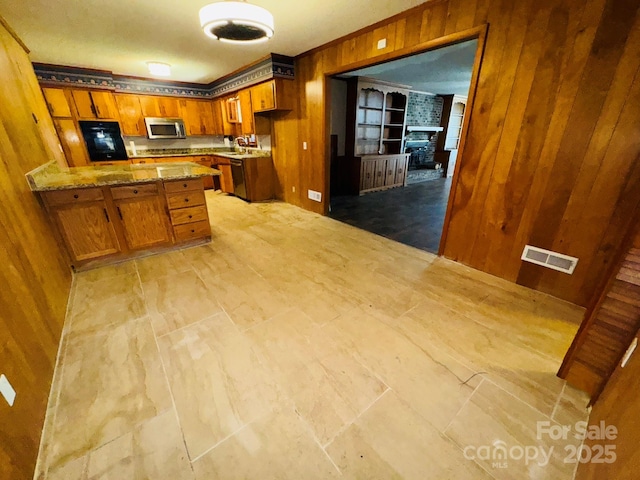 2480 Sumter Hwy, Bishopville, SC 29010 - kitchen featuring brown cabinets, wooden walls, stainless steel microwave, ornamental molding, and visible vents