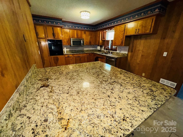 2480 Sumter Hwy, Bishopville, SC 29010 - kitchen featuring wooden walls, visible vents, brown cabinets, and black appliances