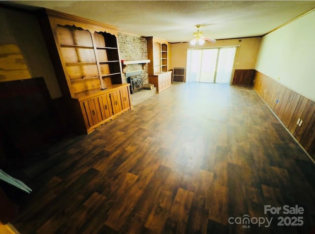 2480 Sumter Hwy, Bishopville, SC 29010 - unfurnished living room featuring a ceiling fan, wood finished floors, wainscoting, wooden walls, and built in features